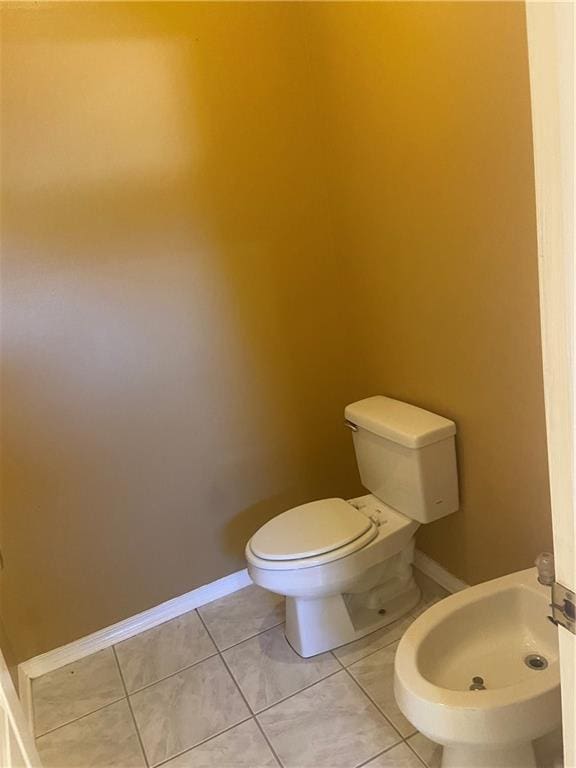 bathroom featuring tile patterned flooring, toilet, and a bidet