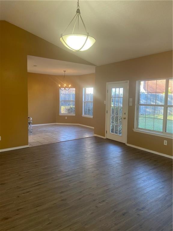 unfurnished room with lofted ceiling, dark wood-type flooring, and an inviting chandelier