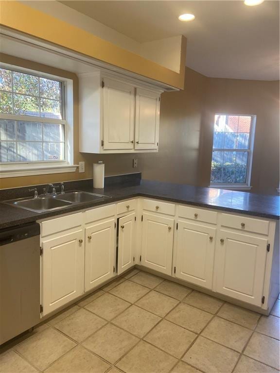 kitchen with light tile patterned floors, sink, dishwasher, white cabinets, and kitchen peninsula