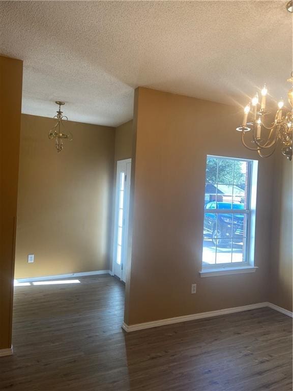 unfurnished room featuring dark wood-type flooring, a notable chandelier, and a textured ceiling