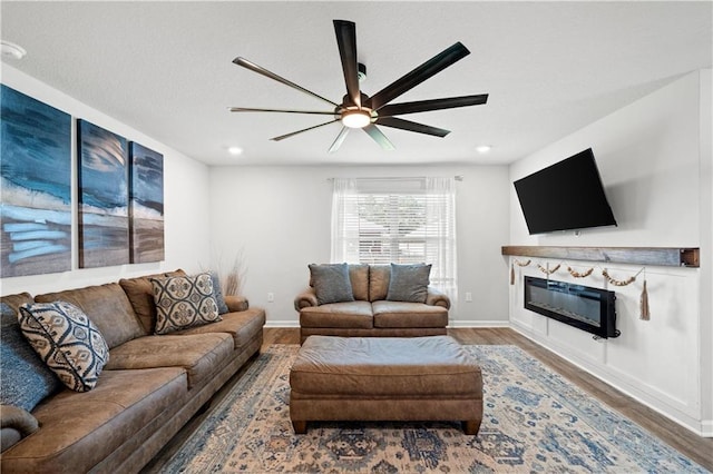 10520 Wales Ln, Spanish Fort, AL 36527 - living area featuring wood finished floors, a ceiling fan, a glass covered fireplace, baseboards, and recessed lighting