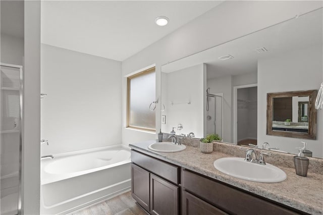 10520 Wales Ln, Spanish Fort, AL 36527 - bathroom featuring a shower stall, wood finished floors, double vanity, a spacious closet, and a bath