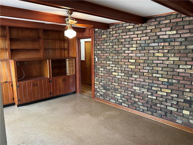 unfurnished living room featuring wood walls, brick wall, a ceiling fan, and beam ceiling