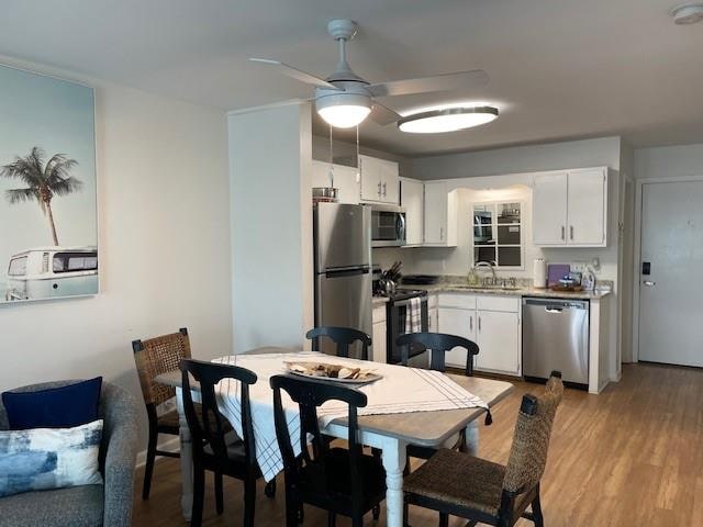 kitchen with light wood-type flooring, white cabinets, appliances with stainless steel finishes, and ceiling fan