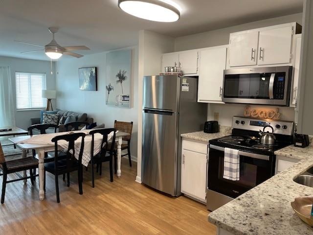 kitchen featuring white cabinetry, light hardwood / wood-style flooring, light stone counters, and stainless steel appliances