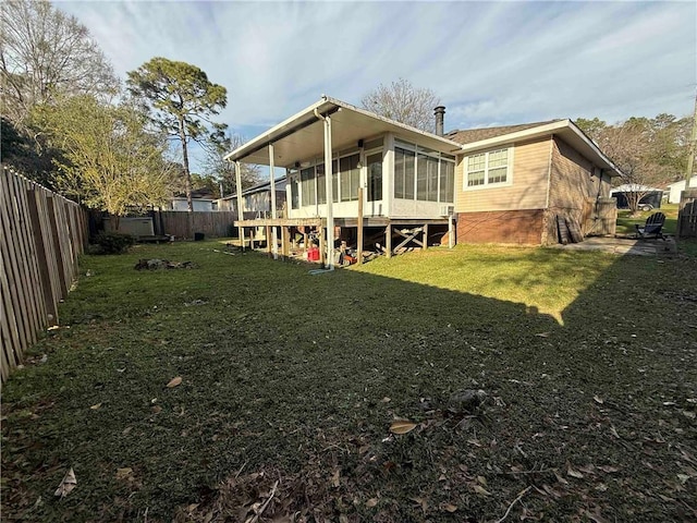 back of property with a lawn, a fenced backyard, and a sunroom