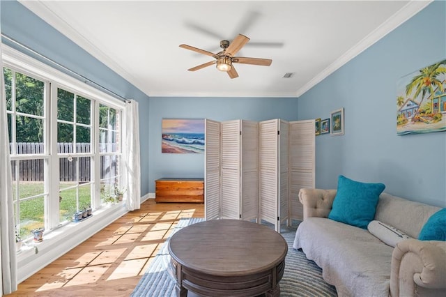 sitting room featuring a ceiling fan, visible vents, baseboards, ornamental molding, and light wood-style flooring