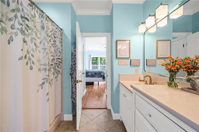 bathroom with tile patterned floors, ornamental molding, baseboards, and vanity