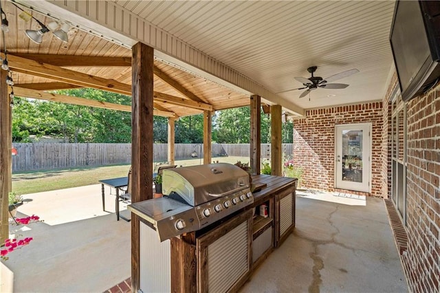 view of patio featuring a fenced backyard, a ceiling fan, a grill, and an outdoor kitchen
