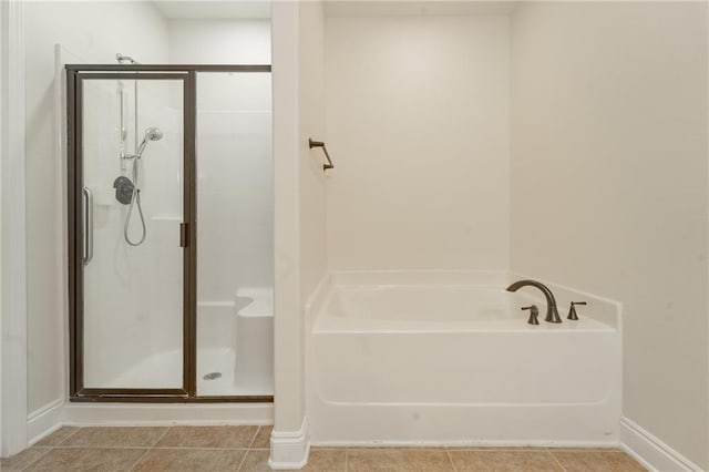 bathroom with a stall shower, baseboards, a bath, and tile patterned floors