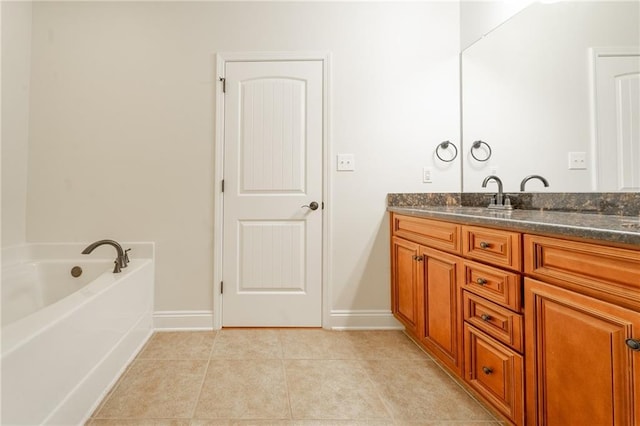 full bath featuring tile patterned flooring, a garden tub, vanity, and baseboards