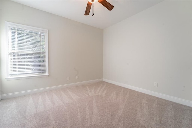 carpeted empty room featuring ceiling fan and baseboards