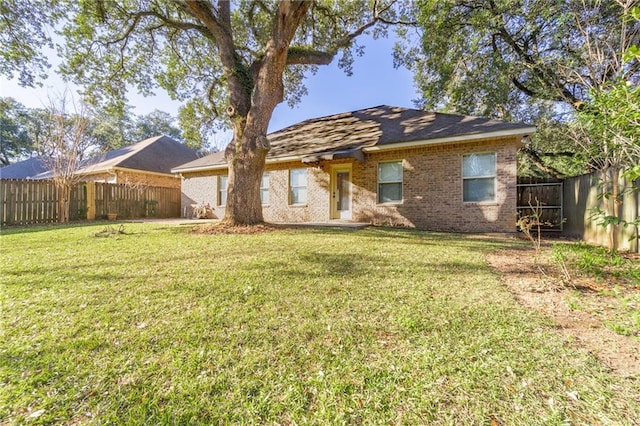 view of front facade featuring brick siding, a front yard, and a fenced backyard