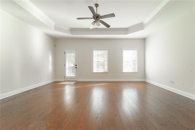 unfurnished room with wood finished floors, a raised ceiling, and crown molding