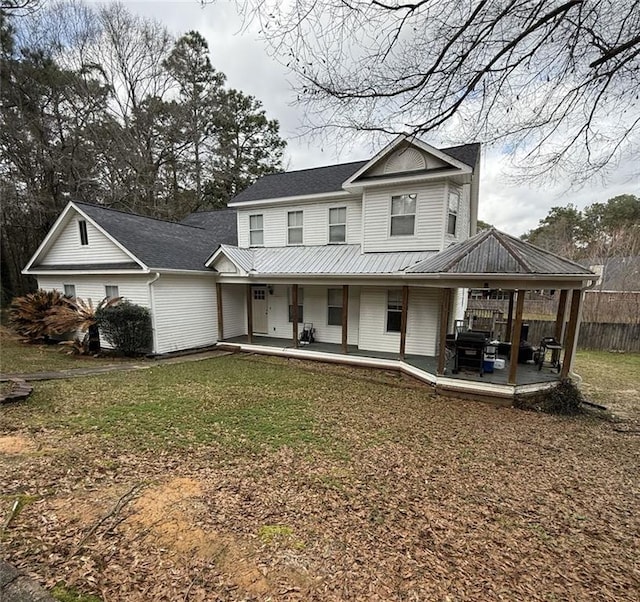 view of front of house featuring metal roof, fence, a front lawn, and a patio