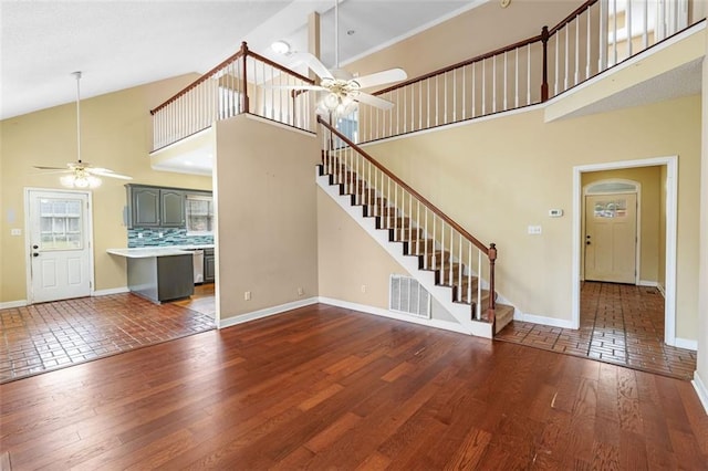 unfurnished living room featuring baseboards, stairway, ceiling fan, and wood finished floors