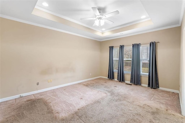 empty room with carpet floors, a tray ceiling, baseboards, and a ceiling fan