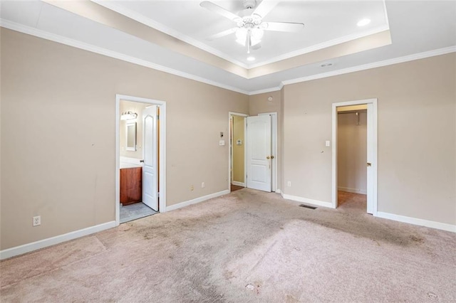 unfurnished bedroom featuring carpet floors, a tray ceiling, and baseboards