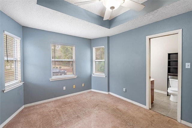 unfurnished bedroom featuring carpet, connected bathroom, a textured ceiling, and baseboards