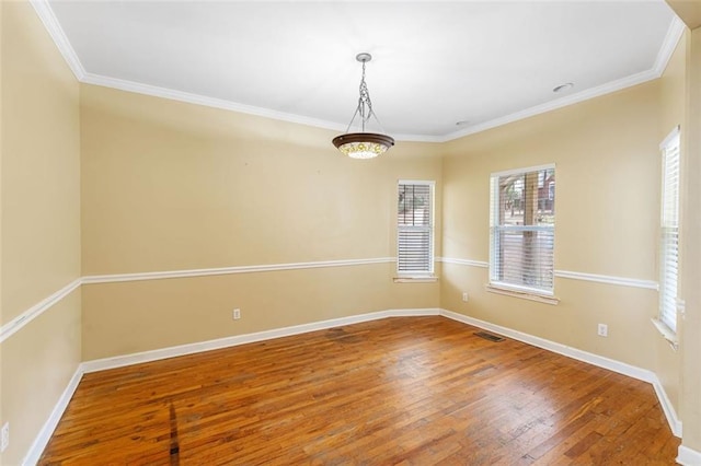 empty room featuring wood-type flooring, visible vents, and baseboards