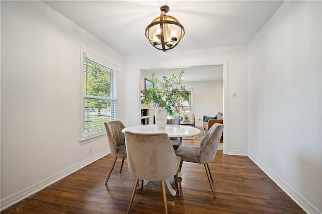 dining space with dark wood-style flooring, a notable chandelier, and baseboards