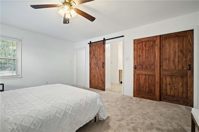 bedroom featuring baseboards, a barn door, a ceiling fan, and carpet flooring