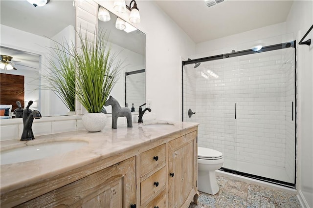 bathroom with double vanity, a shower stall, toilet, and a sink