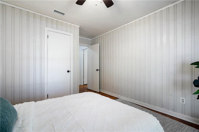 bedroom featuring wood finished floors, a ceiling fan, visible vents, baseboards, and a closet