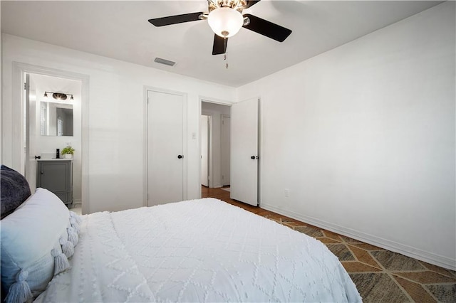 bedroom featuring visible vents, ceiling fan, baseboards, and ensuite bathroom