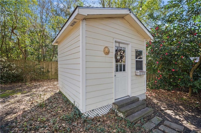 view of shed featuring entry steps and fence