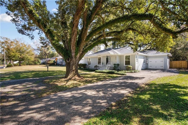 ranch-style home featuring a garage, driveway, a front yard, and fence