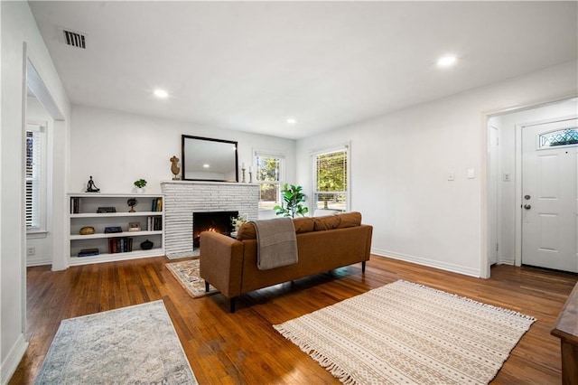 living area with a fireplace, visible vents, wood finished floors, and recessed lighting