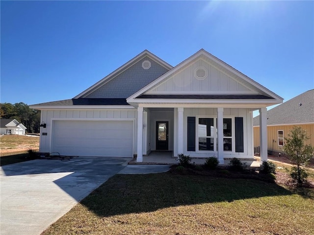 view of front of home with covered porch, a front yard, and a garage