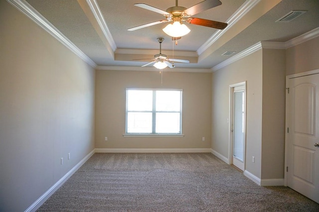 carpeted empty room with a raised ceiling, visible vents, crown molding, and baseboards