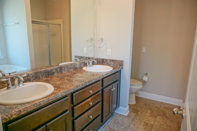 bathroom featuring baseboards, double vanity, a sink, and a shower stall