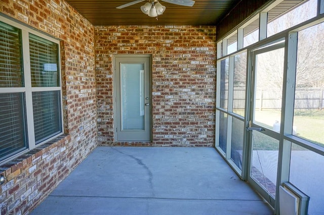 unfurnished sunroom with plenty of natural light and a ceiling fan