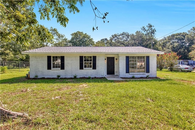 ranch-style home featuring brick siding, a front yard, and fence