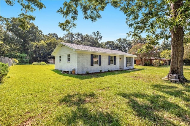 exterior space with brick siding, a front lawn, and fence