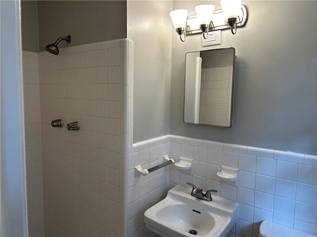 bathroom featuring sink, tiled shower, and tile walls