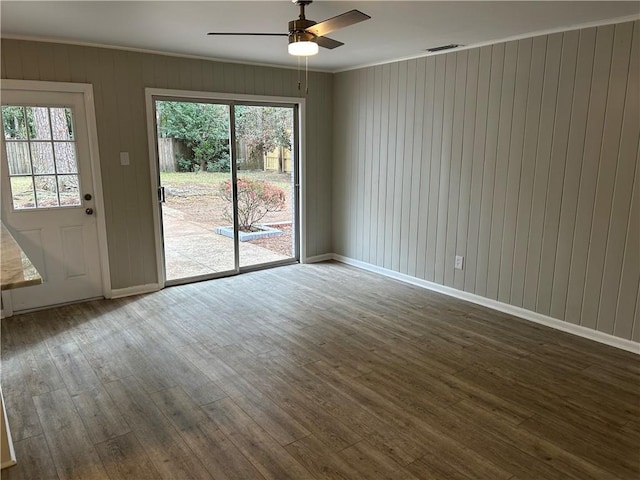 spare room with ornamental molding, wood walls, ceiling fan, and hardwood / wood-style floors