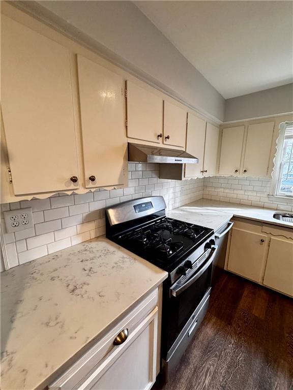 kitchen with tasteful backsplash, cream cabinets, gas range, and dark wood-type flooring