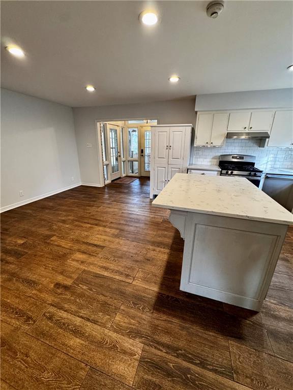 kitchen with white cabinetry, a center island, dark hardwood / wood-style flooring, and stainless steel gas range