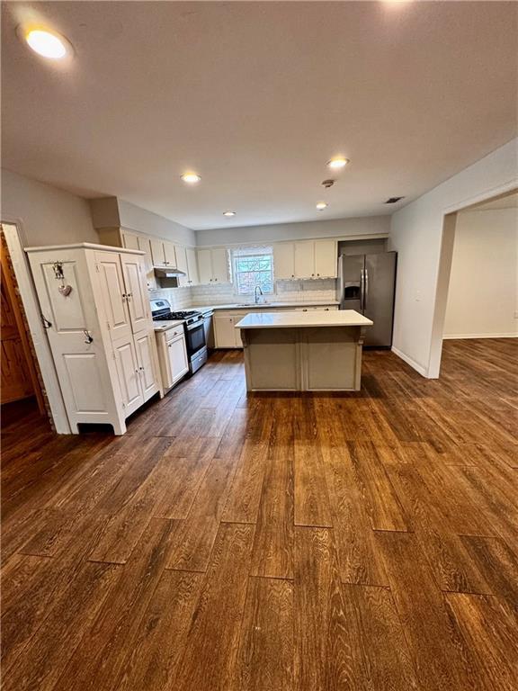 kitchen featuring sink, appliances with stainless steel finishes, a center island, white cabinets, and dark hardwood / wood-style flooring