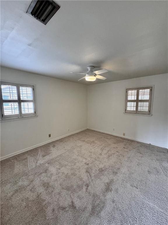 empty room with plenty of natural light, carpet, and ceiling fan