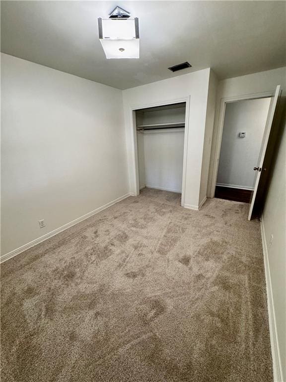 unfurnished bedroom with light colored carpet and a closet