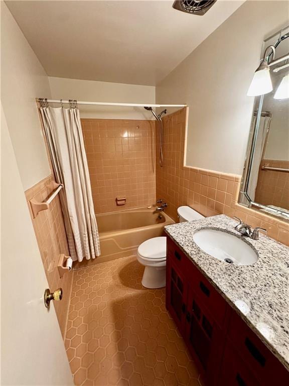 full bathroom with tile patterned floors, toilet, tile walls, vanity, and shower / bathtub combination with curtain