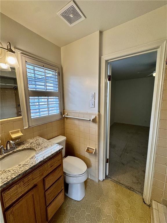 bathroom featuring tile walls, vanity, and toilet