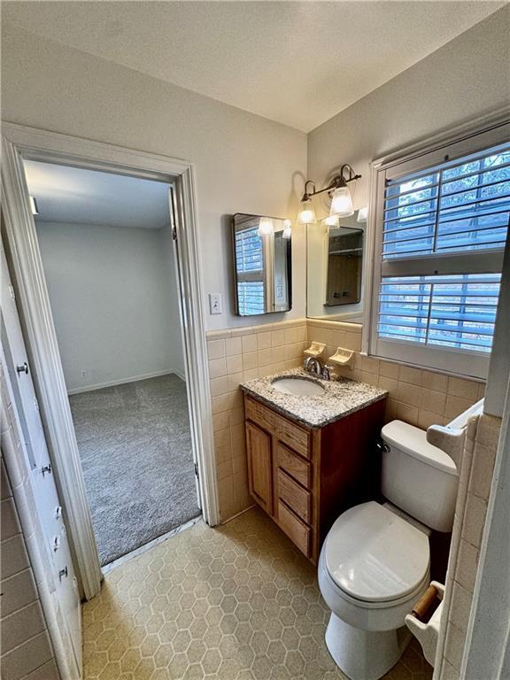 bathroom with vanity, tile walls, and toilet