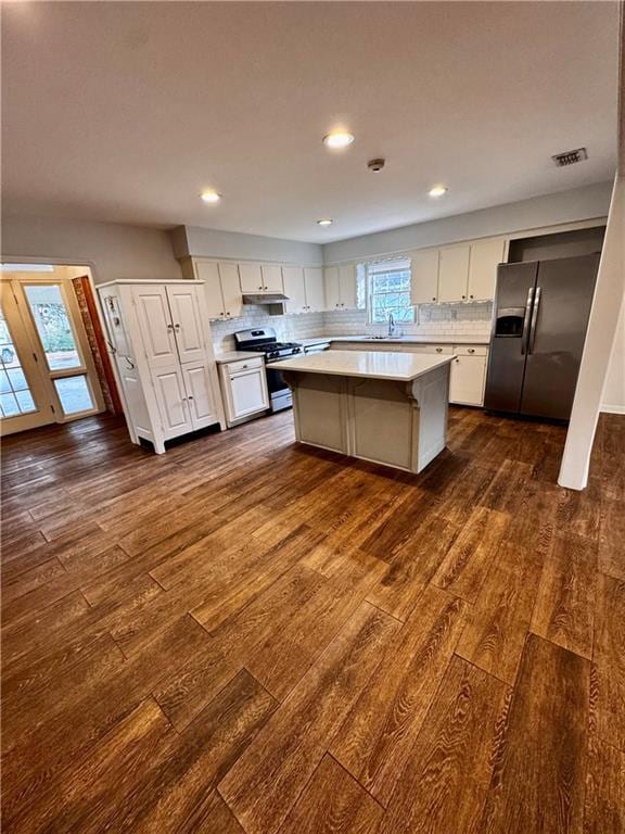 kitchen with stainless steel appliances, a center island, decorative backsplash, and white cabinets