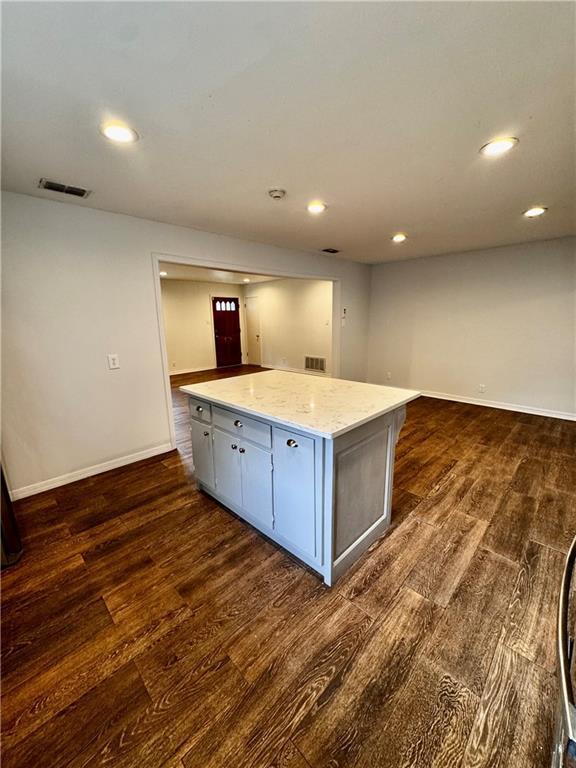 kitchen featuring dark hardwood / wood-style flooring, light stone countertops, and a kitchen island